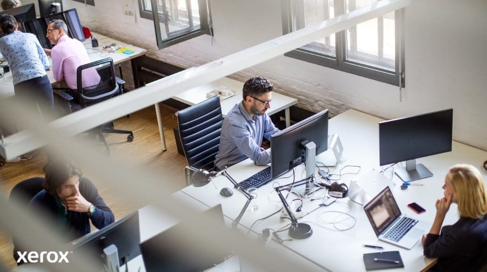 Vue a&eacute;rienne d'un espace de bureau ouvert o&ugrave; plusieurs personnes travaillent &agrave; leur bureau, devant un ordinateur. La sc&egrave;ne &eacute;voque un environnement de travail productif et collaboratif.